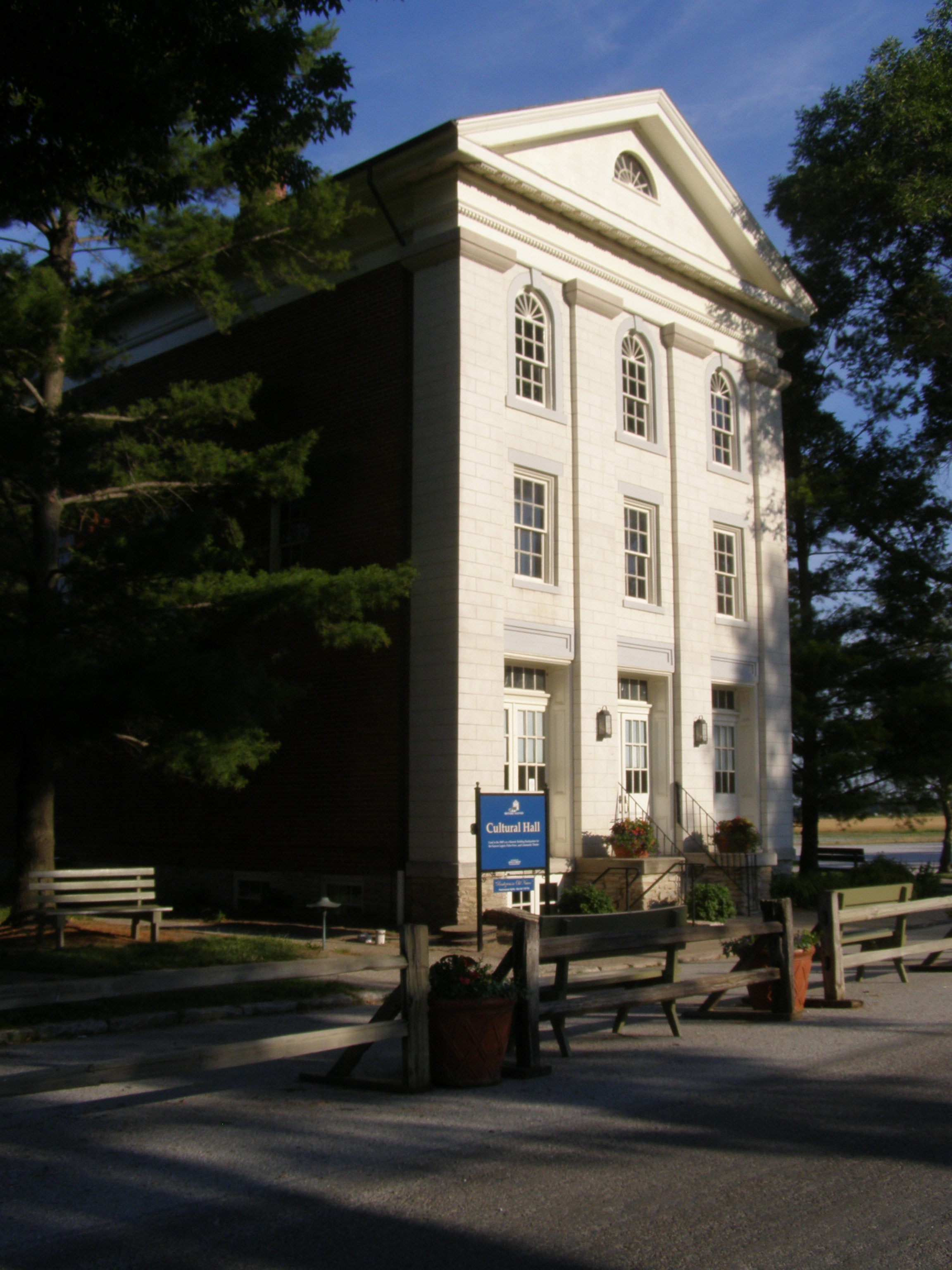 Color photograph of the restored Nauvoo Cultural Hall (Masonic Hall) — a two-story Greek Revival brick building with shuttered windows and a symmetrical façade, standing on the documented Masonic Lodge site in Nauvoo, Illinois.