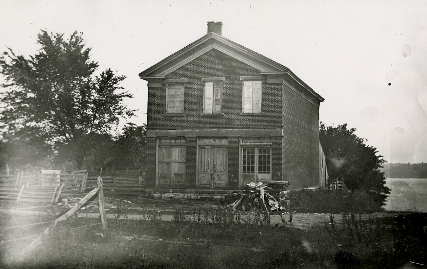 Black-and-white 1885 photograph of Joseph Smith's Red Brick Store in Nauvoo, Illinois — a two-and-a-half-story brick building with a gabled roof, shown in disrepair some four decades after the first endowment was administered in its upper room.